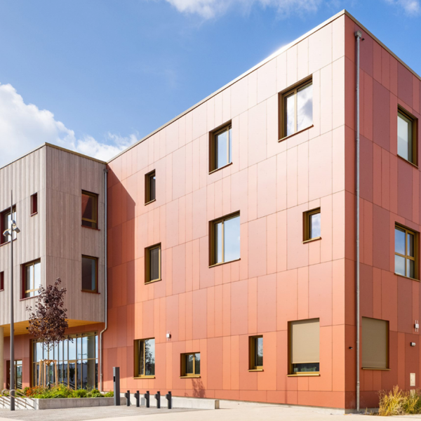 Fachada ventilada em fibrocimento EQUITONE Natura com acabamento mineral vermelho aplicado em edifício contemporâneo